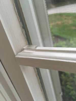A close-up photo of the Andersen Window grille clip holding the wooden grille in place against the window glass